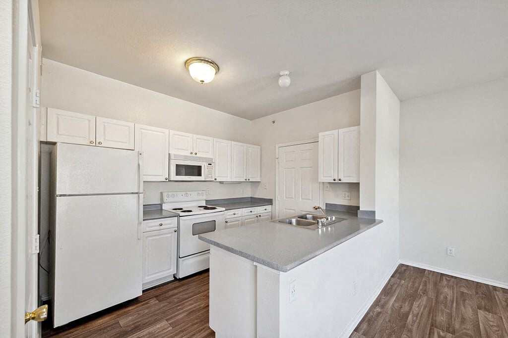 A bright, open kitchen with hardwood floors at the Tivoli Apartments in Dallas, Texas.